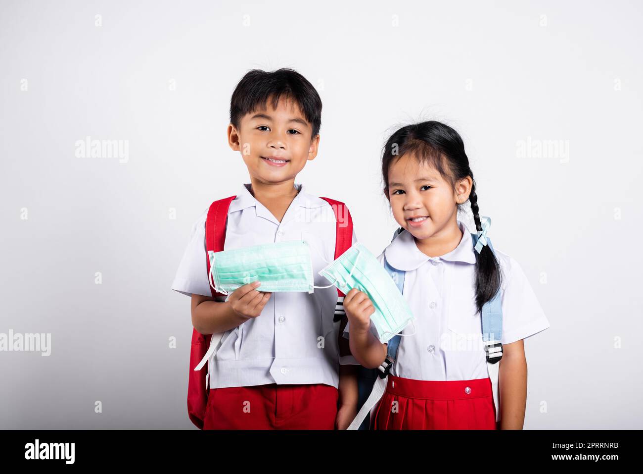 Deux asiatique étudiant enfant fille garçon frère soeur portant l'uniforme thaïlandais étudiant tenant le masque de protection prêt à aller à l'école Banque D'Images