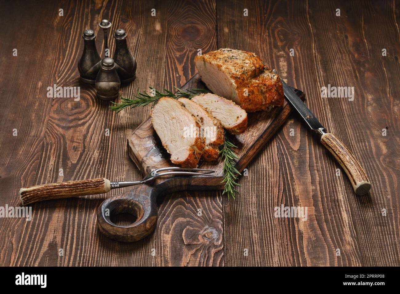Collier de porc joint cuit au four sur une planche de service en bois Banque D'Images