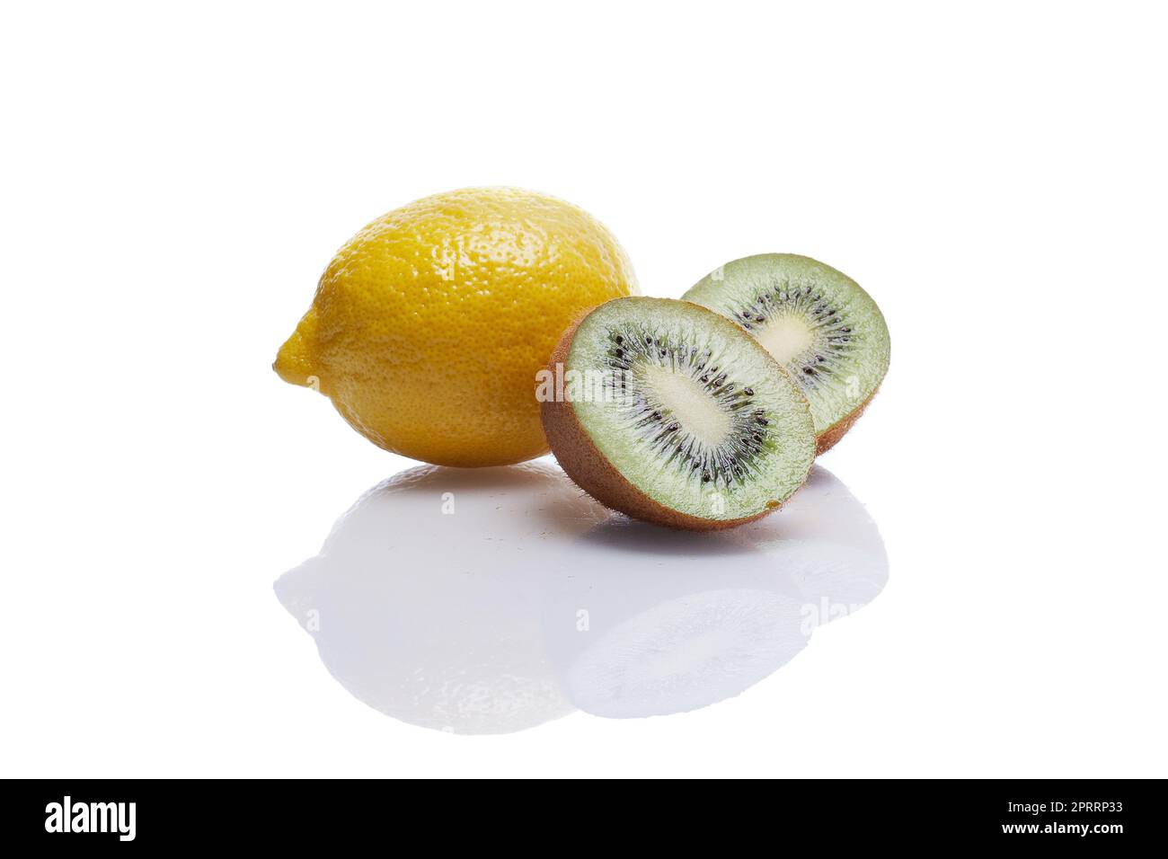 Un citron entier et deux morceaux de kiwi avec réflexion sur une table en verre blanc Banque D'Images