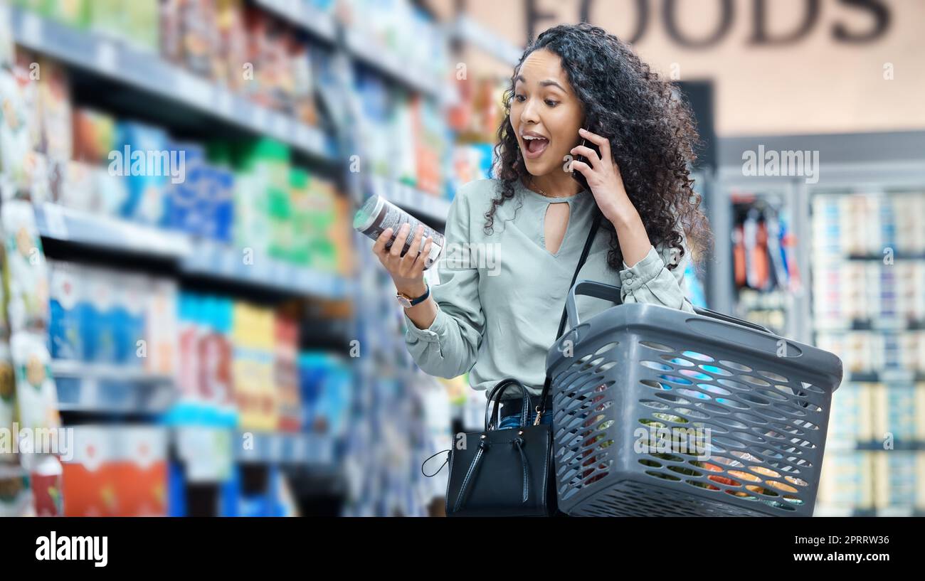 Supermarché, épicerie et surprise d'une femme noire sur un appel téléphonique dans un magasin de détail. Wow, heureux et omg expression faciale d'une affaire d'audition de client, prix de vente sur le stock et de la nourriture de réduction Banque D'Images