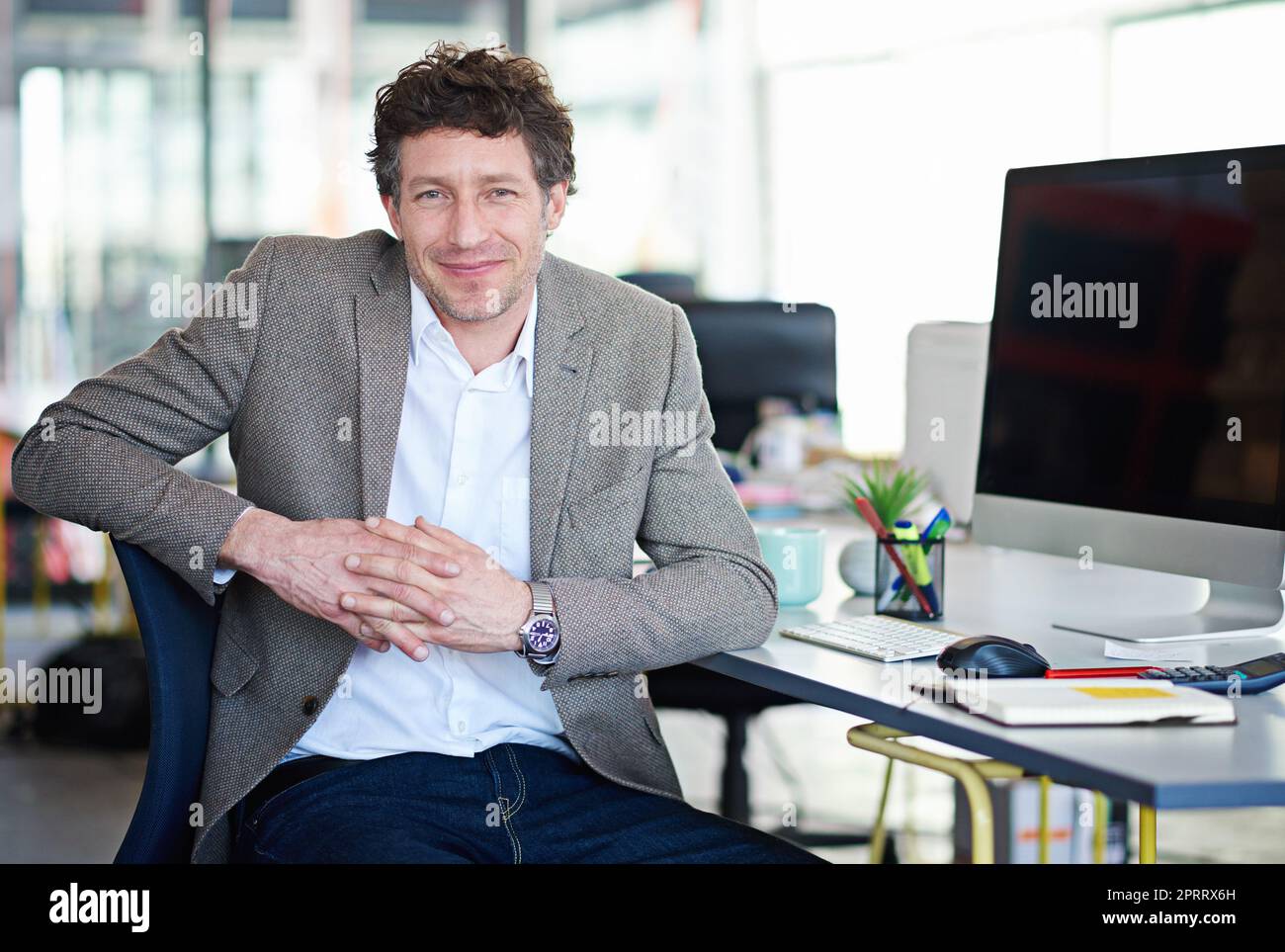 Le visage de la satisfaction au travail. Portrait d'un beau designer assis à son poste de travail dans un bureau Banque D'Images