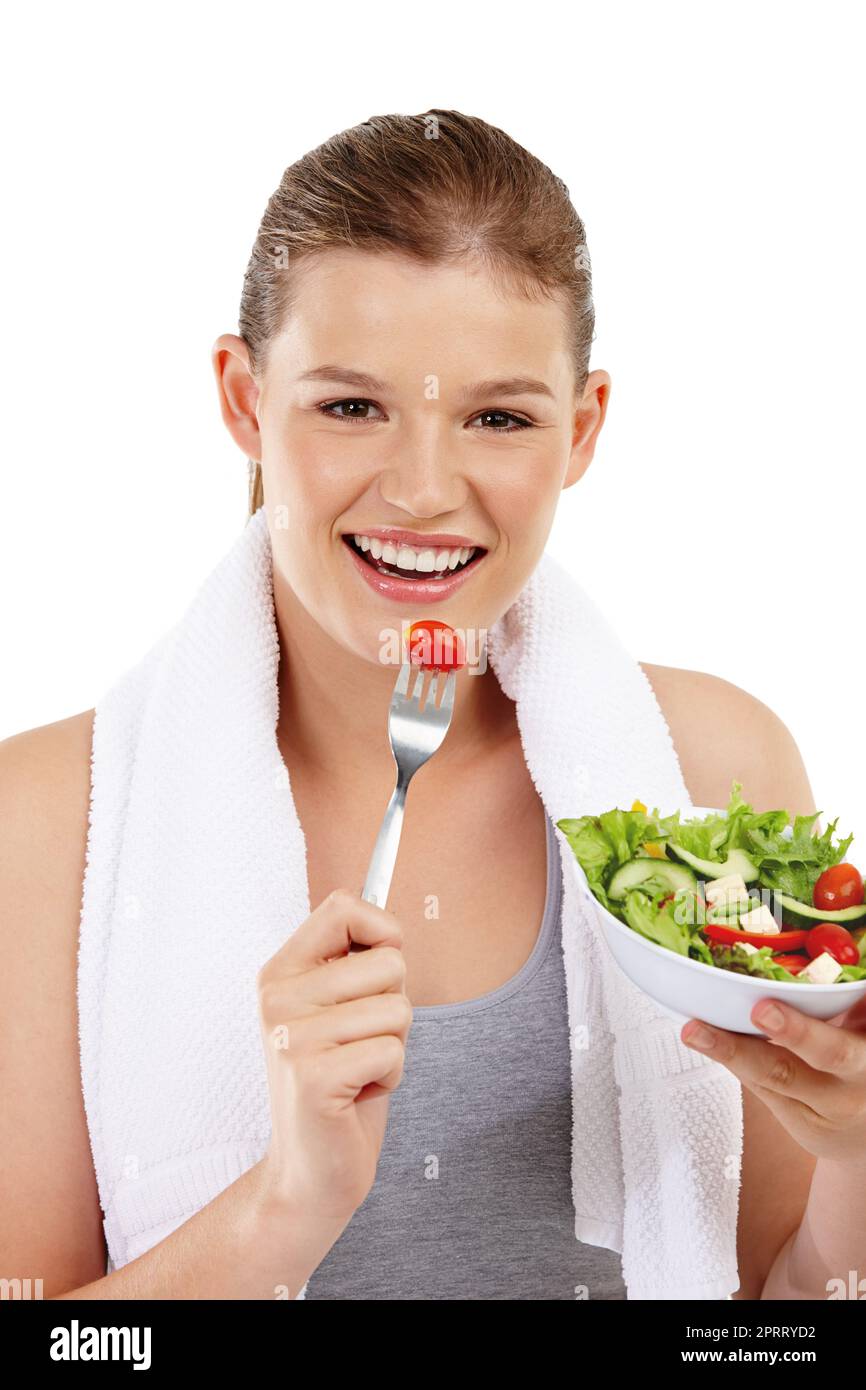 Manger vert pour rester maigre. Prise de vue de la tête et de l'épaule d'une adolescente en bonne santé qui profite d'une salade après un entraînement Banque D'Images