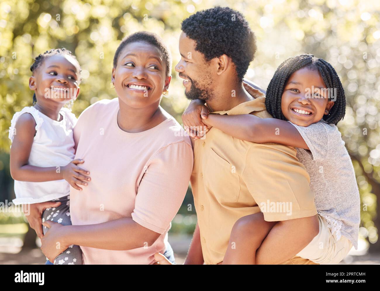 Famille noire, nature et parents transportant des enfants, se lier et passer du temps libre par une journée ensoleillée. Soutien, amour et heureux homme et femme se souciant sur une promenade dans un parc avec leurs filles mignonnes dehors. Banque D'Images