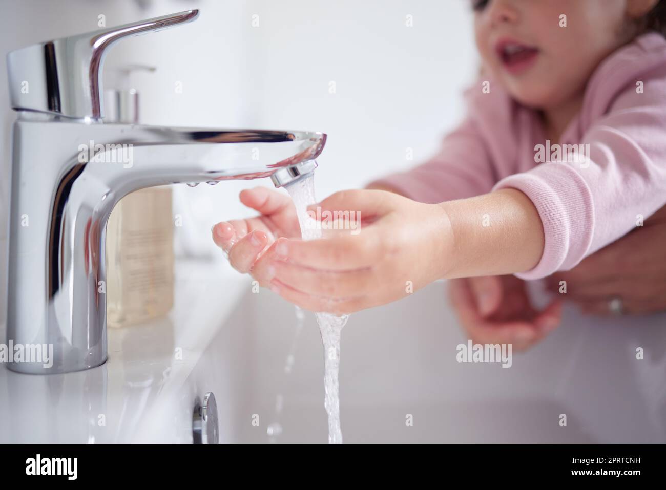 Mains, eau et nettoyage avec une fille et sa mère se lavant les mains sous un robinet pour l'hygiène et l'assainissement pendant le covid dans leur maison. Enfants, santé et toilettage dans la salle de bains d'une maison Banque D'Images