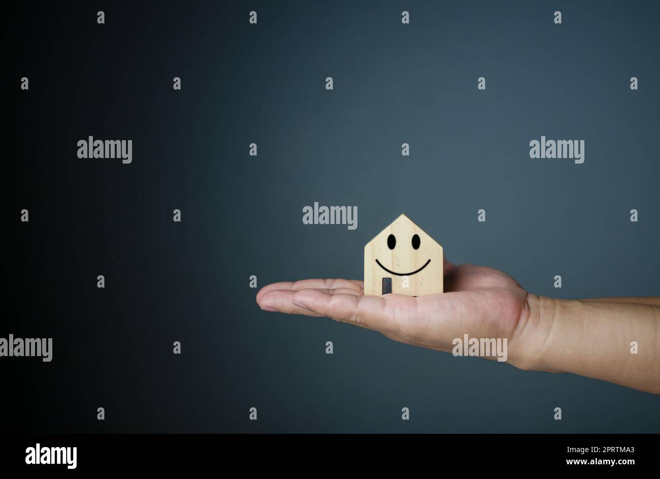 Concept de maison heureuse. Main tenant une maison modèle souriante. Indique le bonheur et l'amour dans la maison. Banque D'Images