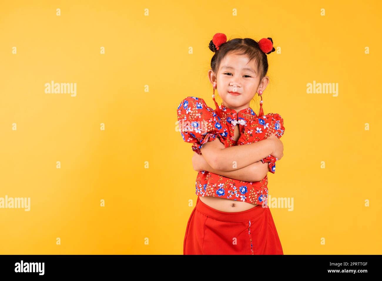 Happy Asian Chinois petite fille sourire porter le cheongsam rouge bras croisés, Portrait enfants en robe traditionnelle avec célébration de salutation pour Chinois ne Banque D'Images