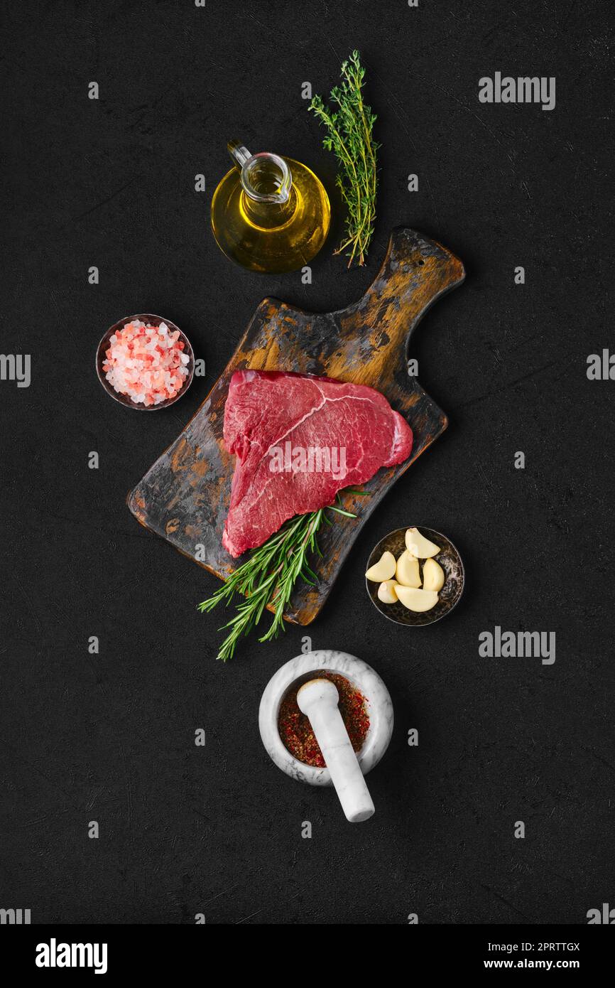 Vue de dessus du steak de l'œil de bœuf cru avec ingrédients pour la cuisson Banque D'Images