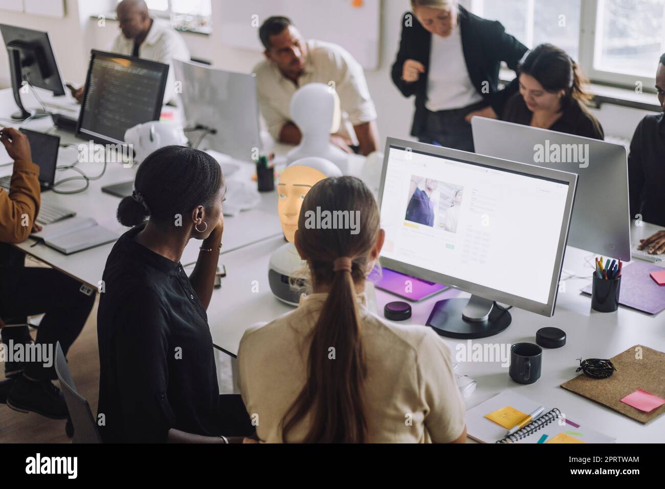 Des doctorants multiraciaux discutent au-dessus de l'ordinateur à un bureau dans un laboratoire d'innovation Banque D'Images