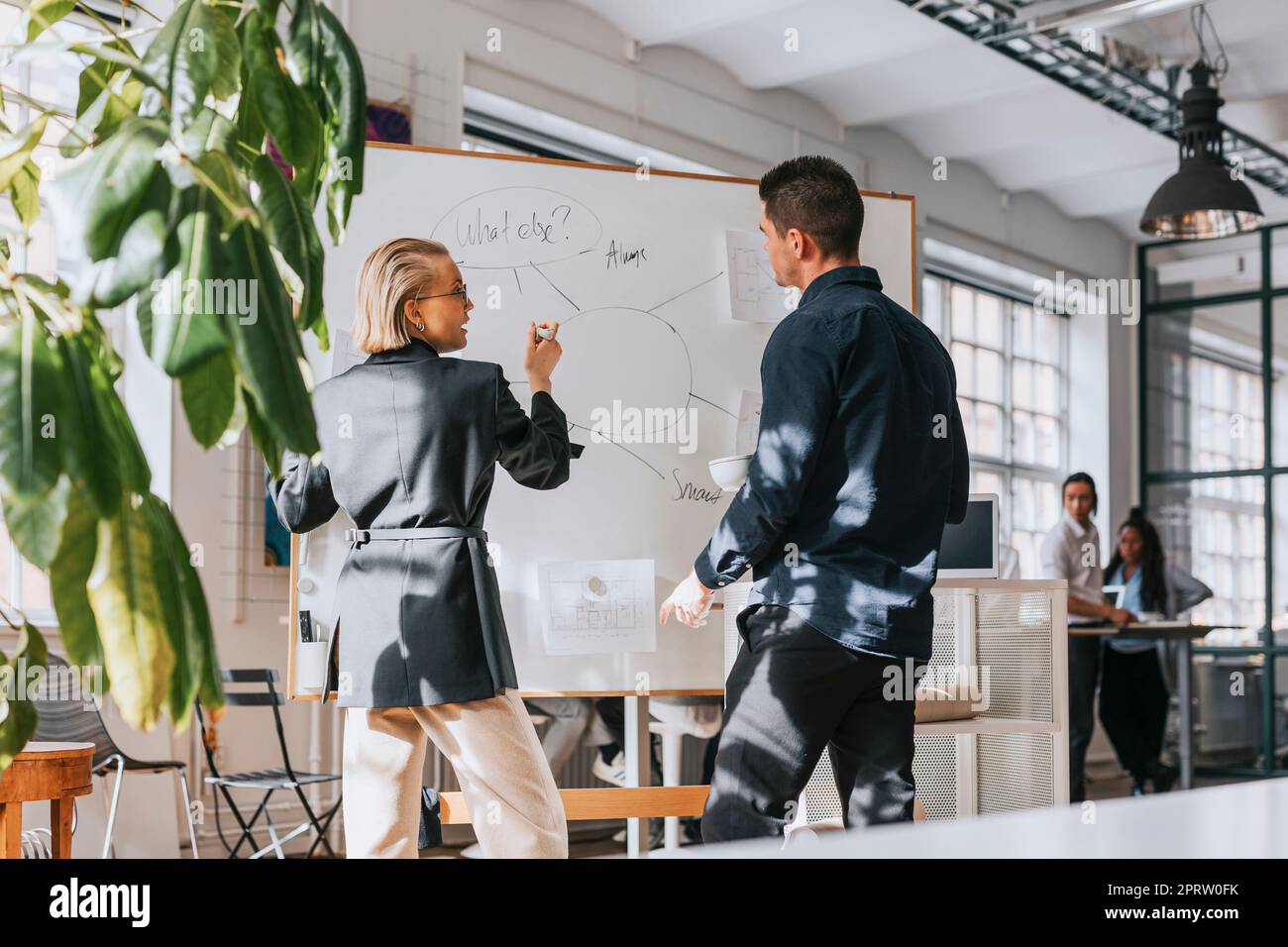 Hommes et femmes d'affaires planification de la stratégie par rapport au tableau blanc au bureau Banque D'Images