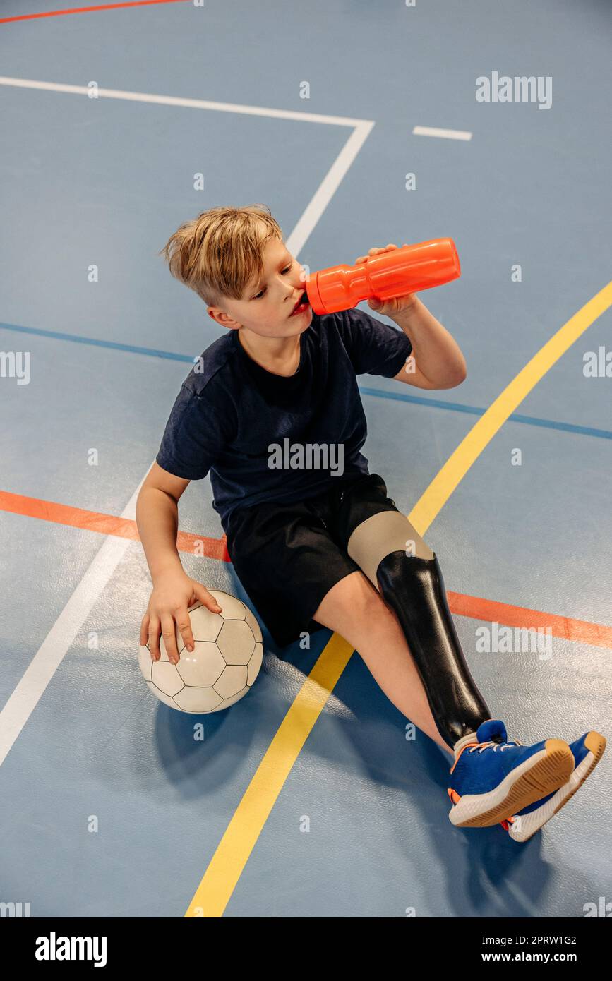 Vue en grand angle de l'eau potable d'un athlète masculin après un match de football sur un terrain de sport Banque D'Images