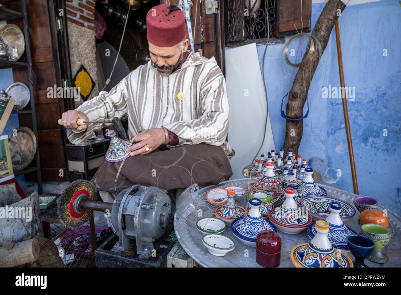 Artisan vêtu de djellaba et chapeau marocain typique travaillant dans les rues de Chefchaouen. Banque D'Images