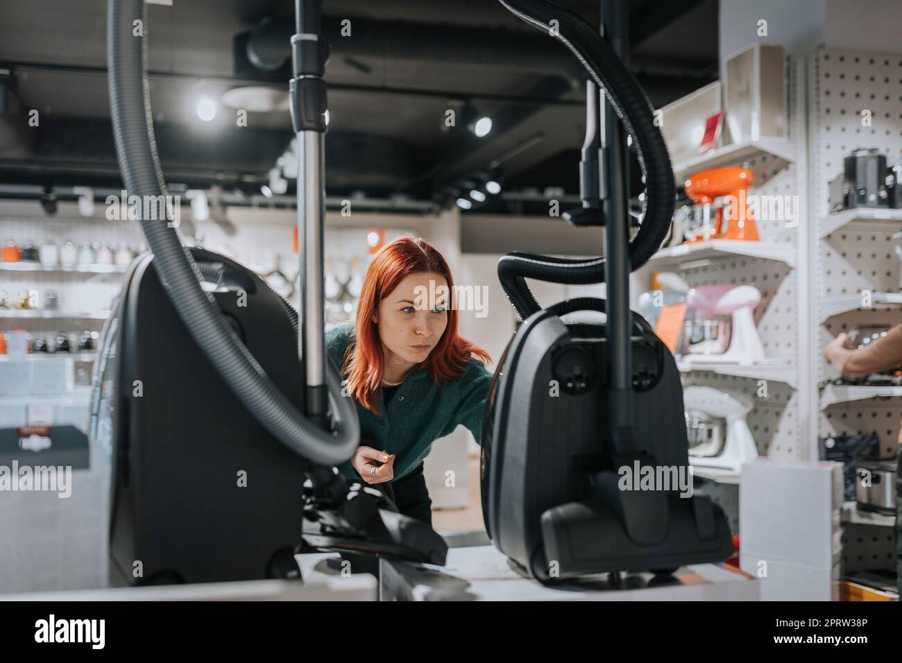 Une cliente examine un aspirateur lorsqu'elle fait ses achats dans un magasin d'électronique moderne Banque D'Images