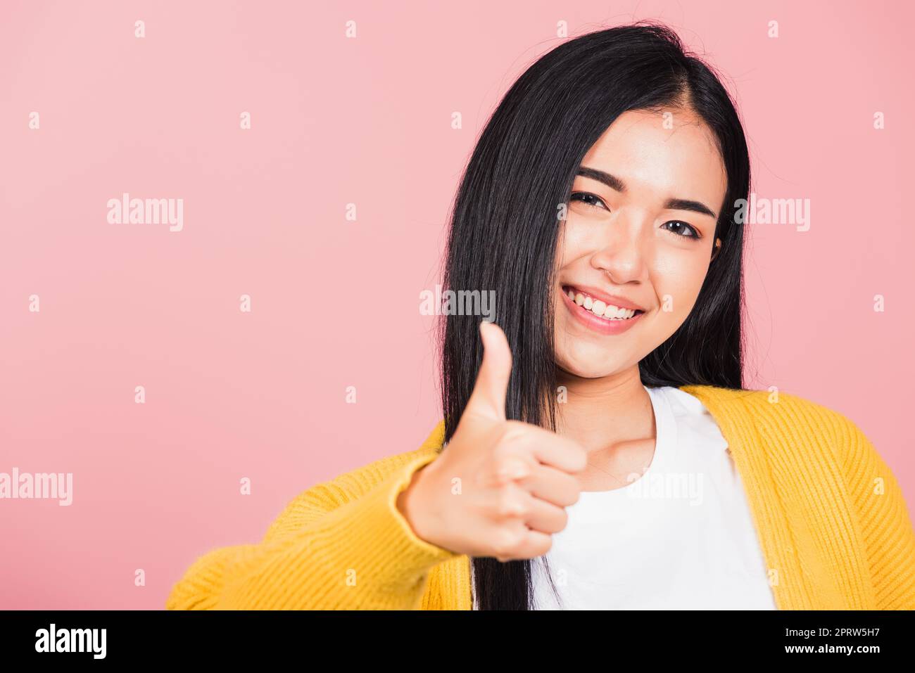 Portrait asiatique belle jeune femme sourire elle debout fait le pouce vers le haut, OK signe pour convenir studio tourné isolé sur fond rose, Thai femelle réussi comme le doigt geste avec l'espace de copie Banque D'Images