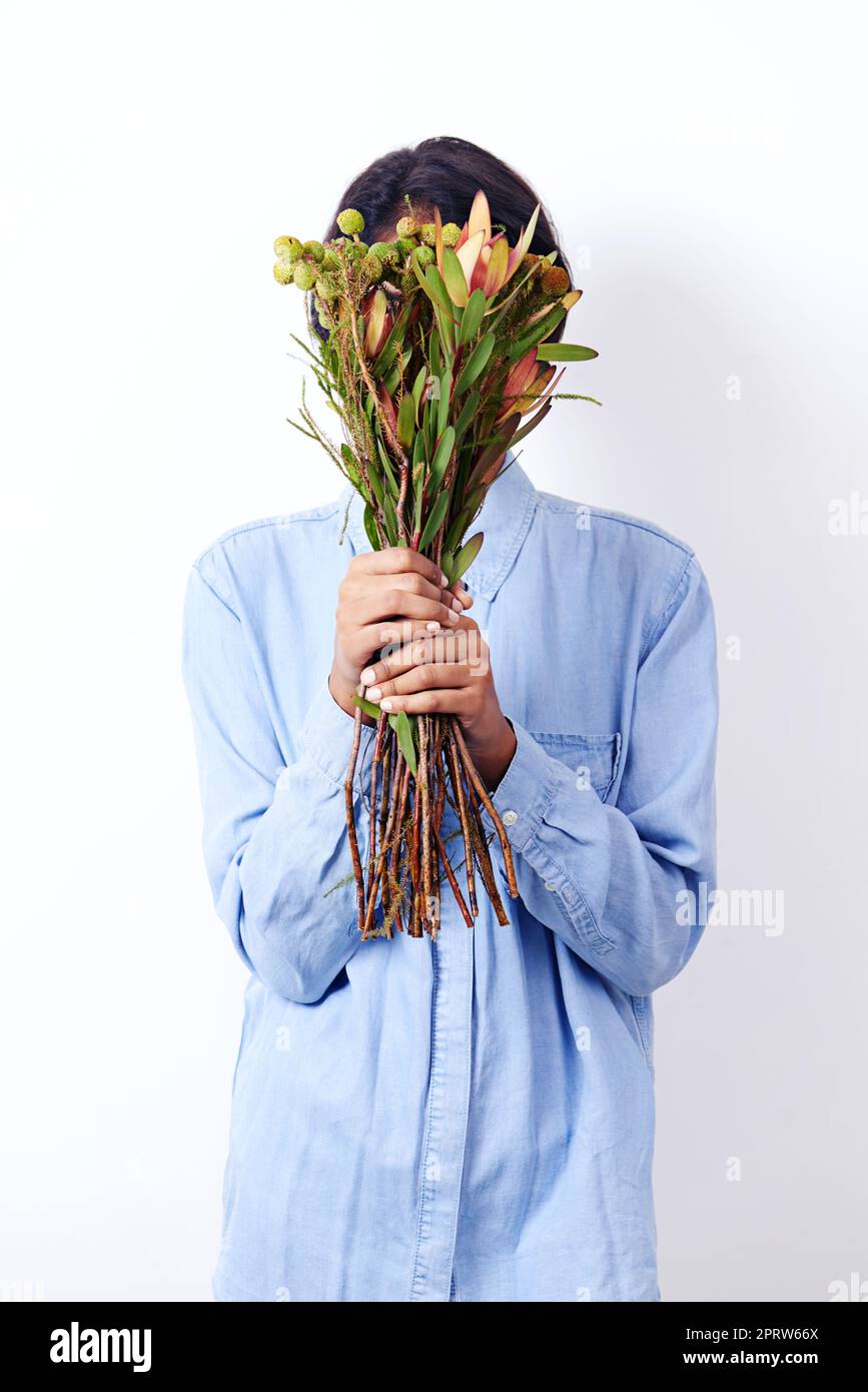 Déesse de la nature. Studio photo d'une jeune femme ethnique attrayante tenant un bouquet de fleurs devant son visage Banque D'Images