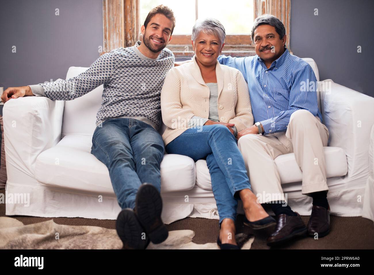 Ce sont toujours ceux vers lesquels je me rends... Portrait d'un couple heureux assis avec leur fils adulte à la maison. Banque D'Images