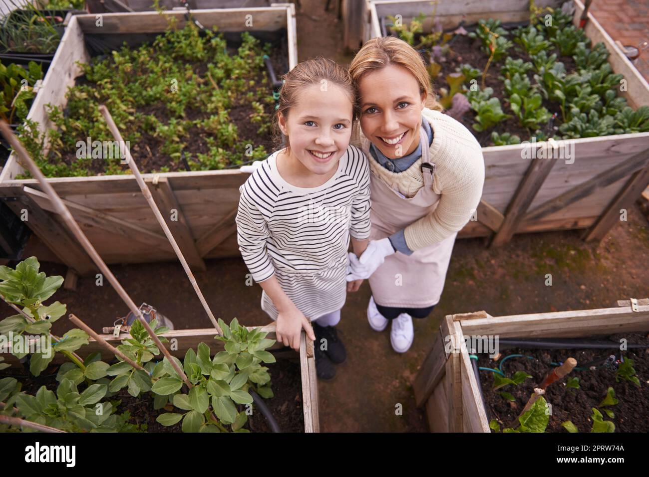 Shes un grand aide à sa mère dans la pépinière. Portrait grand angle d'une mère et d'une fille qui jardinent ensemble dans leur arrière-cour. Banque D'Images