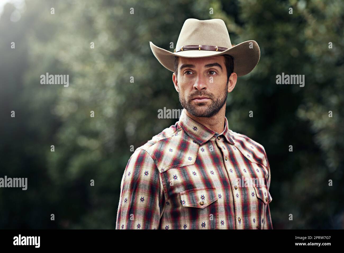 Les cow-boys ont aussi du style. Un beau cowboy portant une chemise à carreaux et stetson Banque D'Images