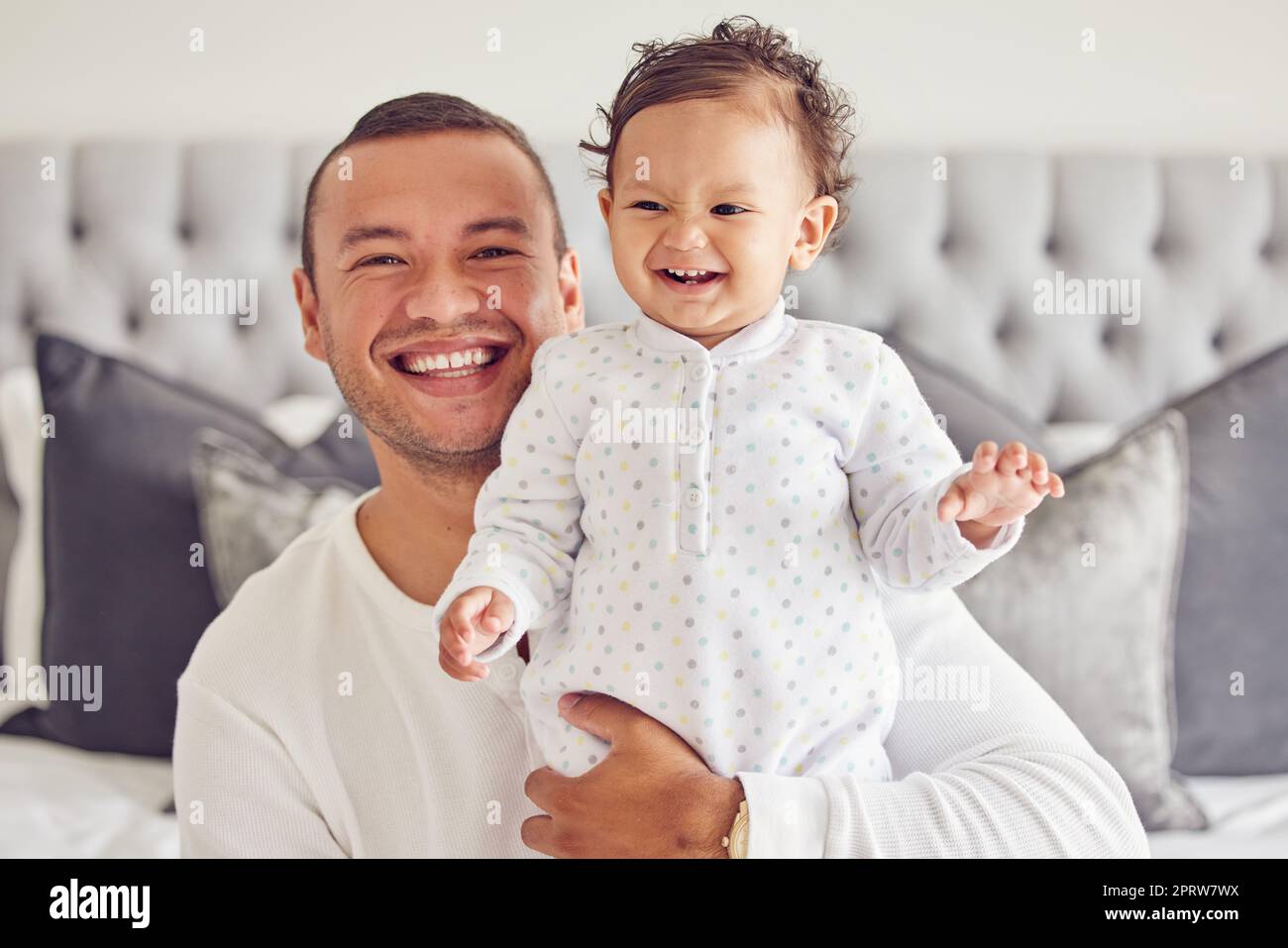 Joyeux père sourire avec bébé, au lit dans un moment mignon ensemble dans la maison ou l'appartement le matin. Un nouveau père enthousiaste avec un jeune enfant, montre l'expression du bonheur et des soins dans la chambre à coucher à la maison familiale Banque D'Images