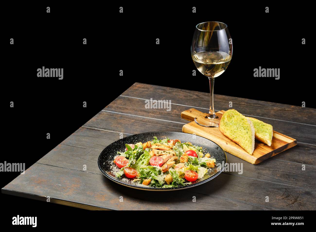 Salade avec filet de poulet, tomate et fromage et verre de vin blanc Banque D'Images