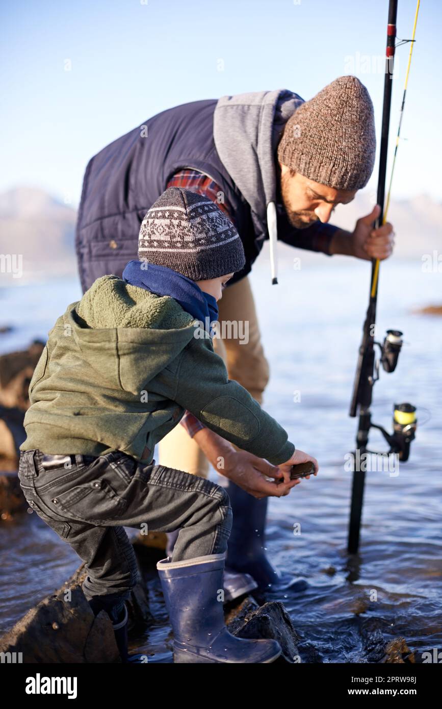 Permettez-moi de voir... un joli petit garçon pêchant avec son père au bord de la mer Banque D'Images