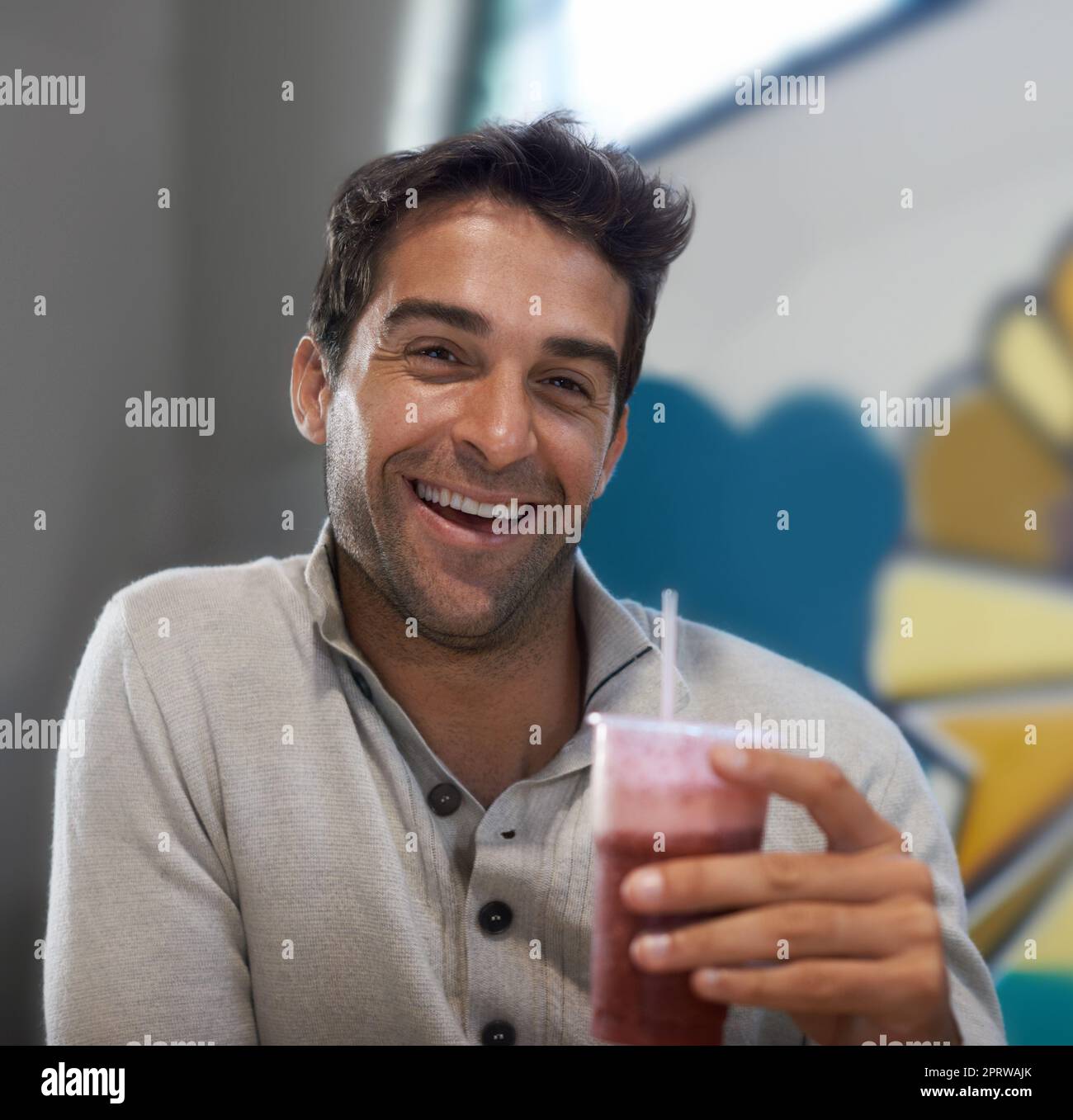 MMM, rafraîchissement. Portrait d'un beau homme qui boit un smoothie dans un restaurant Banque D'Images