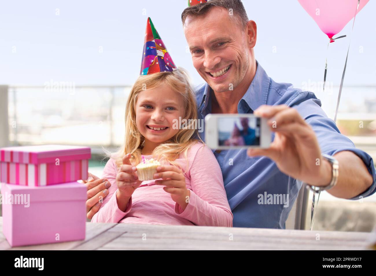 Grandir si vite. Un petit cliché d'un homme heureux prenant une photo de lui-même et de sa jeune fille à l'occasion de son anniversaire. Banque D'Images