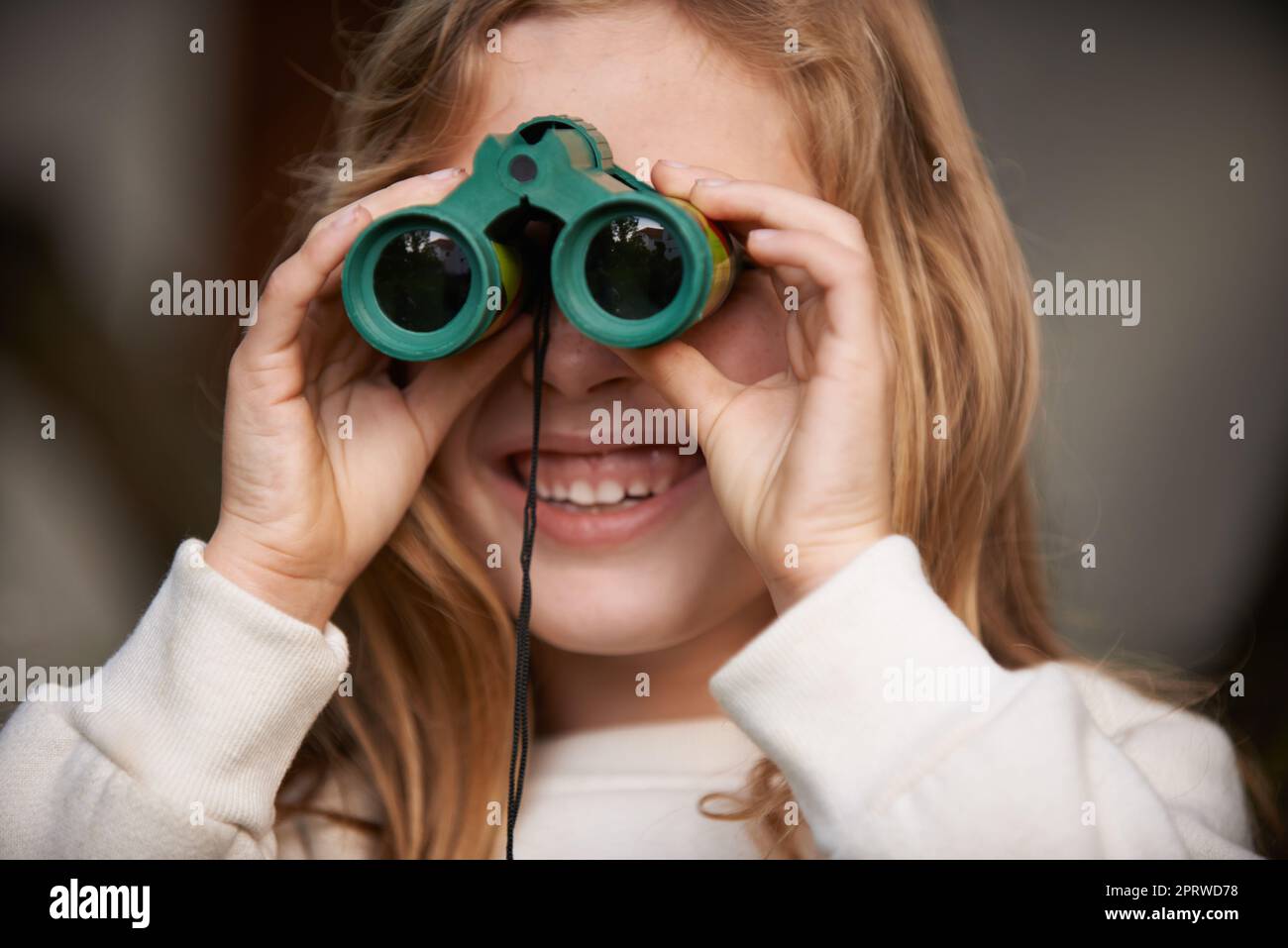 Wow, je peux tout voir avec ces. Jeune fille jouant avec une paire de jumelles Banque D'Images