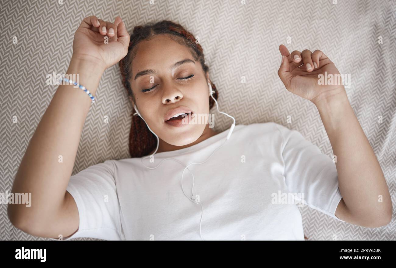 Détendez-vous, dormez et dormez avec une femme qui écoute de la musique tout en dormant dans sa chambre par le dessus. La radio, le podcast et la fréquence de méditation avec la femme utilisant la diffusion de relaxation pour aider à la détente Banque D'Images