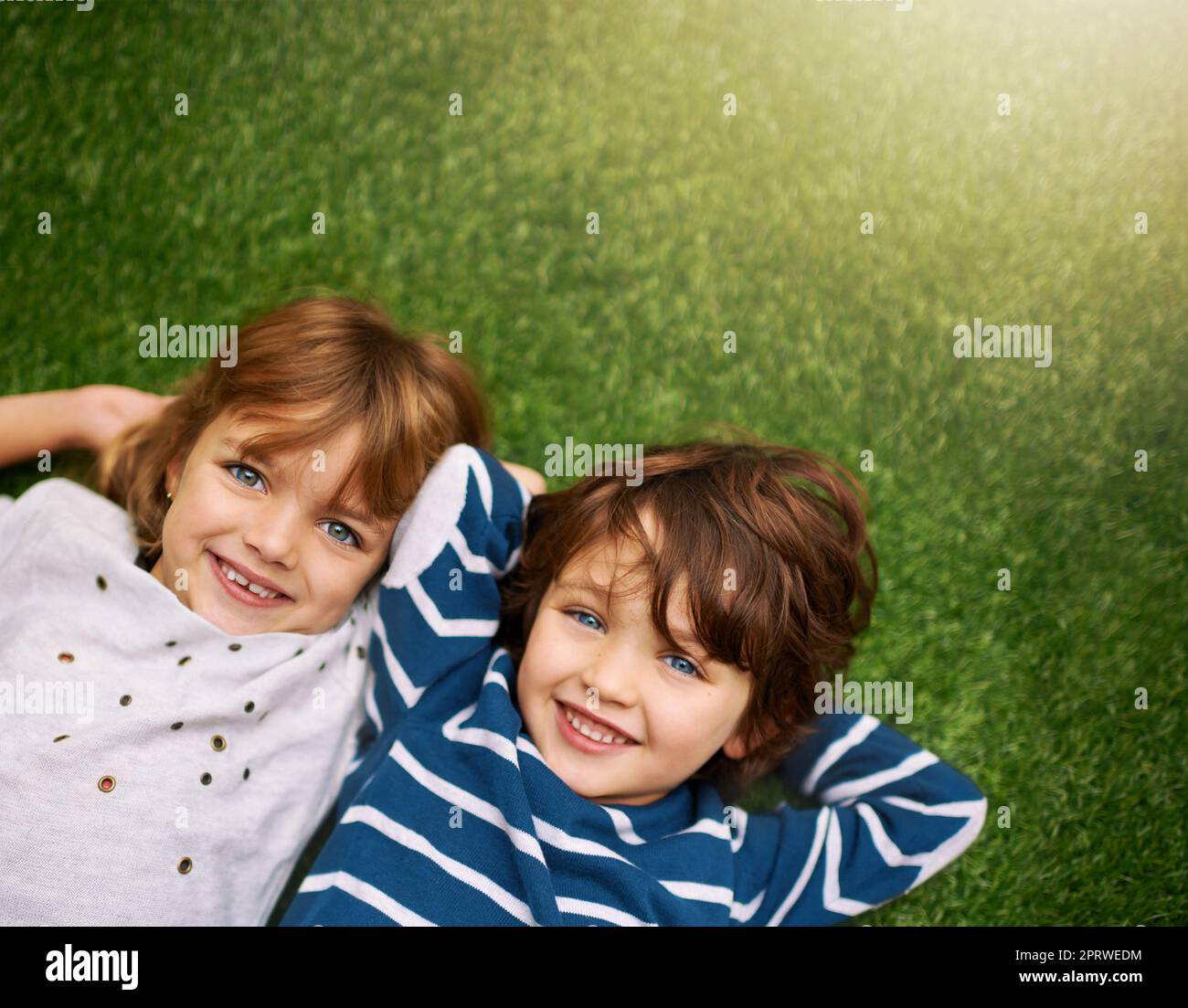 Siblingsjoint côte à côte et coeur à coeur. Frère et sœur se détendant sur l'herbe dans l'arrière-cour Banque D'Images