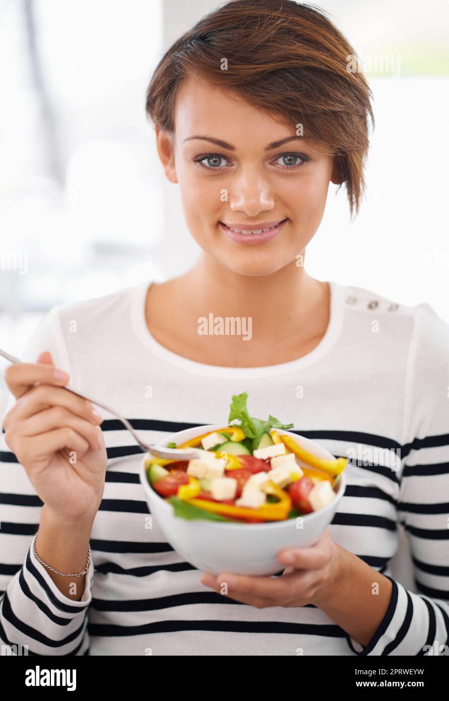 J'ai hâte du manger. Une jeune femme qui a l'air heureuse de sa salade Banque D'Images