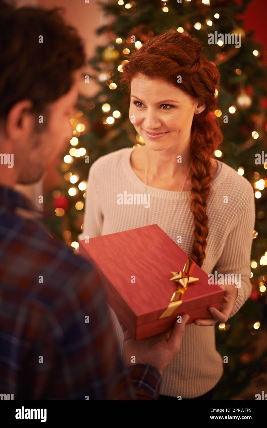 Un jeune couple affectueux qui échange des cadeaux à Noël. Banque D'Images