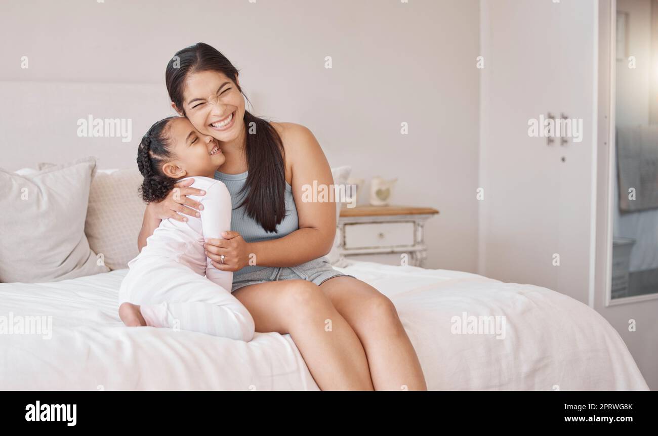 Maman au lit sourire, câlin bonne fille en pyjama le matin à la maison le  week-end ou les jours fériés. Mère avec enfant, exprimer le bonheur et  l'amour dans la chambre à