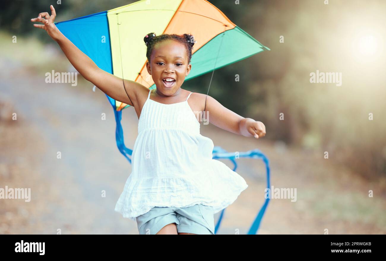 Nature, été et fille avec un cerf-volant courir dans un parc avec un sourire. Week-end, bonheur et un petit enfant noir ayant l'amusement en plein air. Liberté, développement et croissance pour les jeunes enfants heureux jouant à l'extérieur Banque D'Images