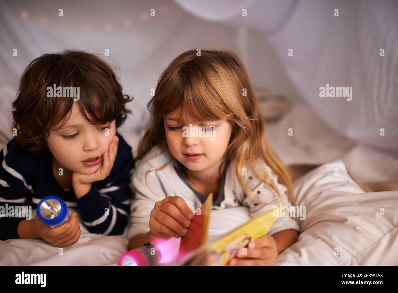 Deux Enfants Avec Une Lampe De Poche Lisent Un Livre Sous Une Couverture En  Guise De Tente