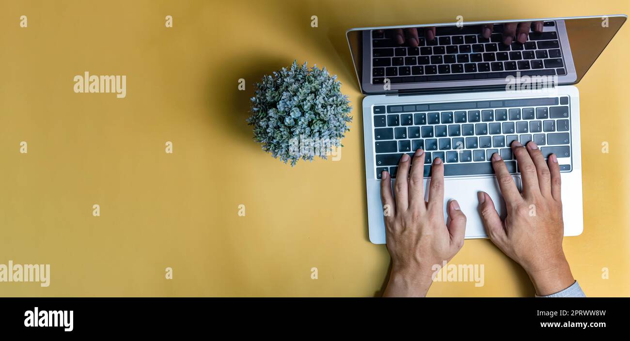 Homme utilisant un clavier ordinateur portable sur fond jaune. Copier l'espace Banque D'Images
