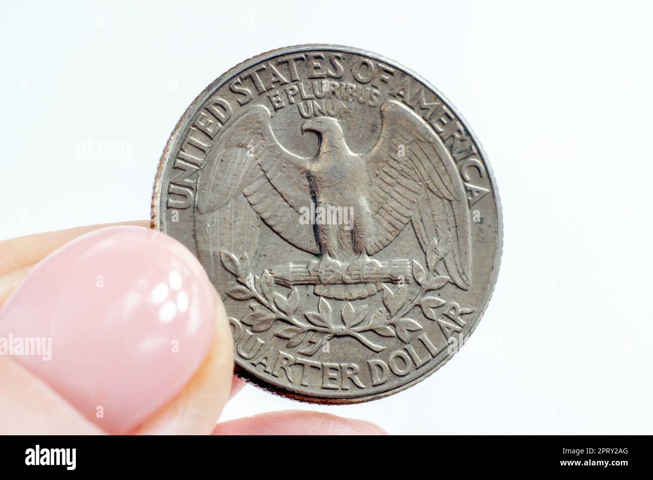 Une femme tient une pièce de monnaie de l'American Quarter Dollar sur un arrière-plan clair de près. Banque D'Images