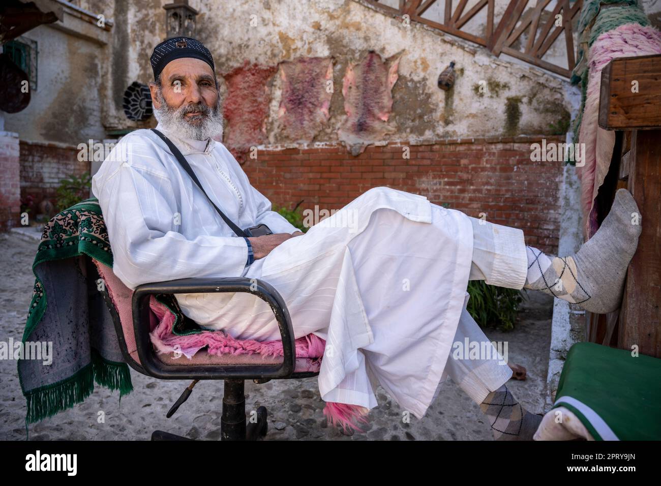 Portrait d'un musulman assis sur une chaise dans les tanneries de Tétouan. Banque D'Images