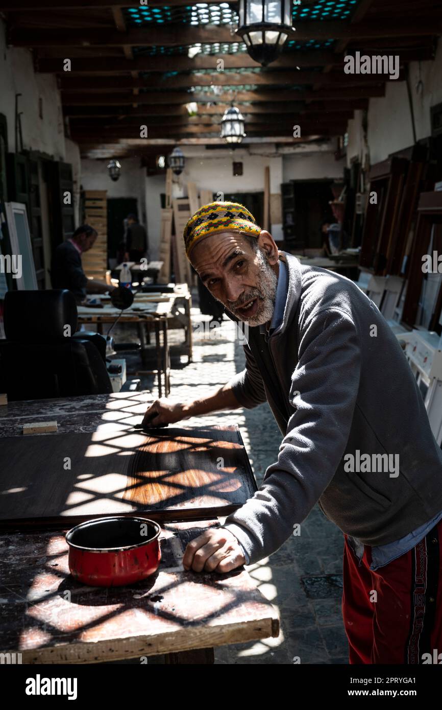 Carpenter vernis un morceau de bois à son poste de travail dans la médina de Tétouan. Banque D'Images