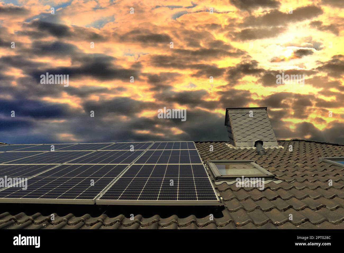 Panneaux solaires produisant de l'énergie propre sur le toit d'une maison résidentielle au coucher du soleil Banque D'Images
