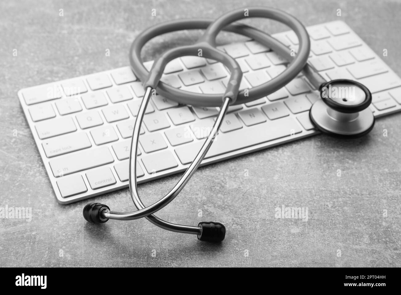 Clavier d'ordinateur avec stéthoscope sur table grise, gros plan Banque D'Images