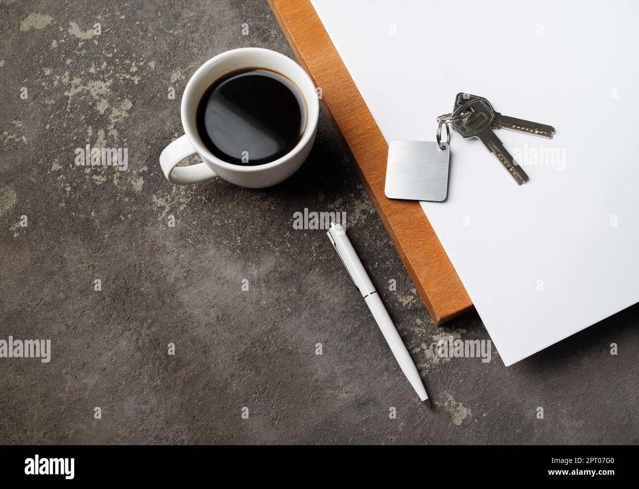 Concept d'agence immobilière. Clés, tasse à café, stylo et papier sur fond de béton. Banque D'Images