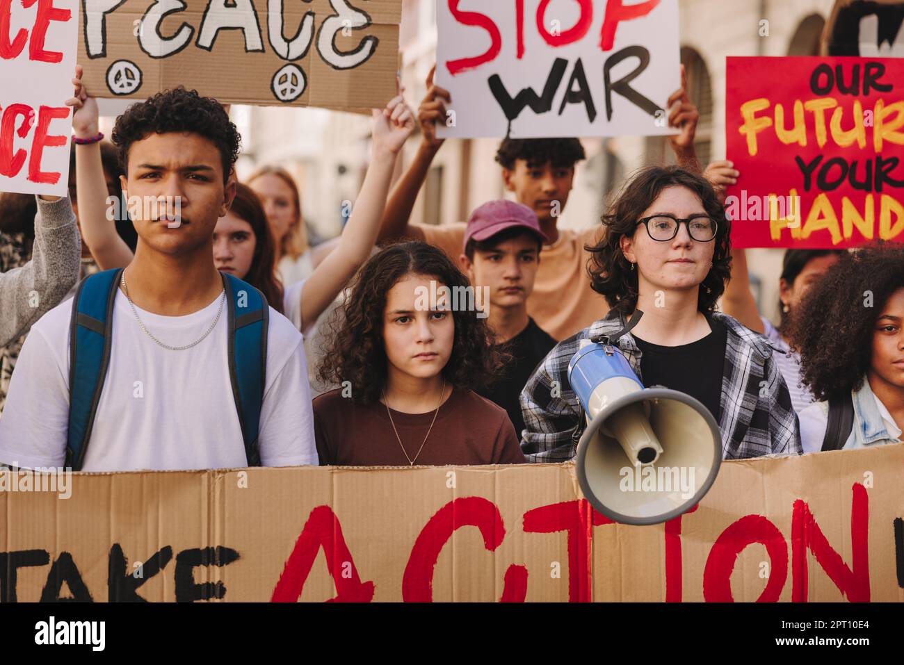 Des jeunes militants brandissant des banderoles et des pancartes lors d'un rassemblement contre la guerre. Groupe de jeunes multiculturels marchant pour la paix mondiale. Les démons adolescents Banque D'Images