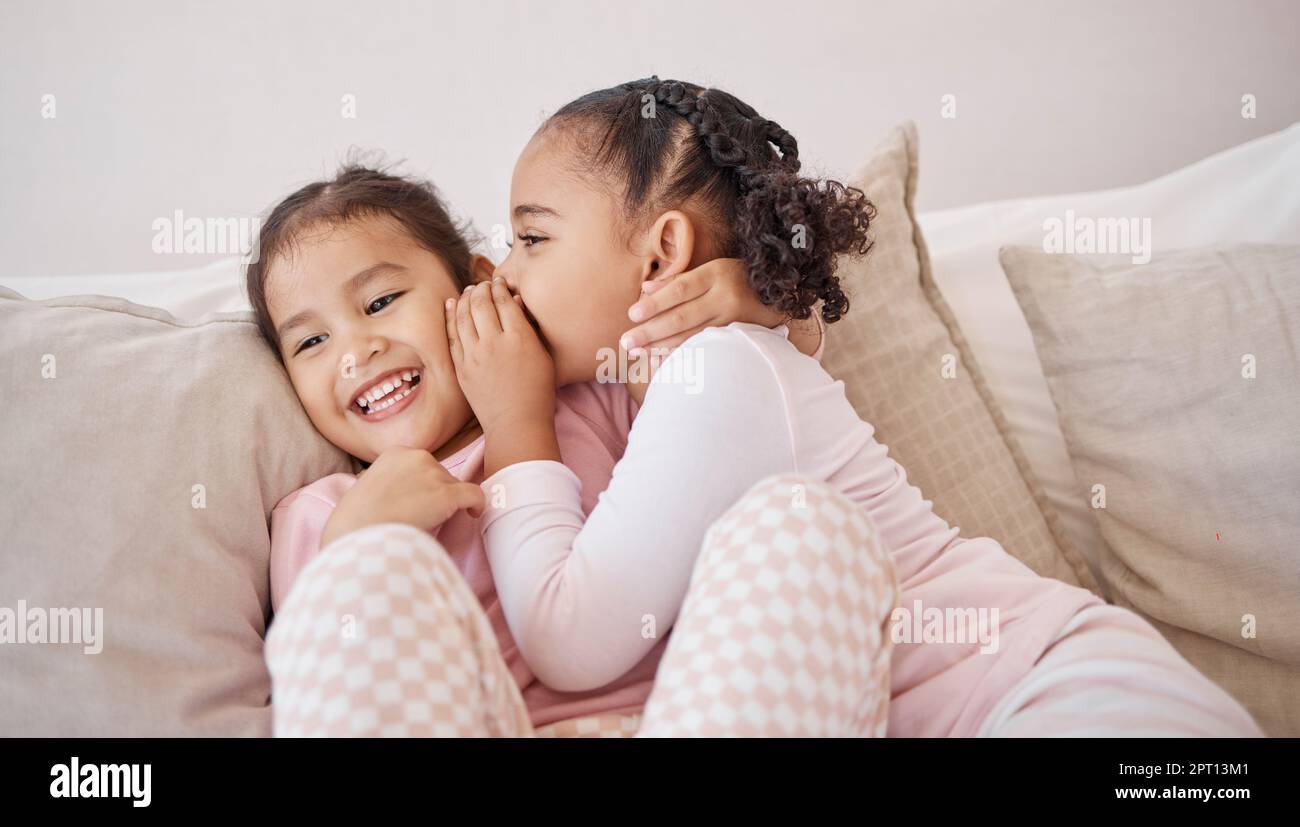 Une fille, des amis ou des enfants chuchotent le secret à un ami sur le canapé tout en se détendant ensemble le jour du jeu. Communication, conversation et sœurs ou vous Banque D'Images