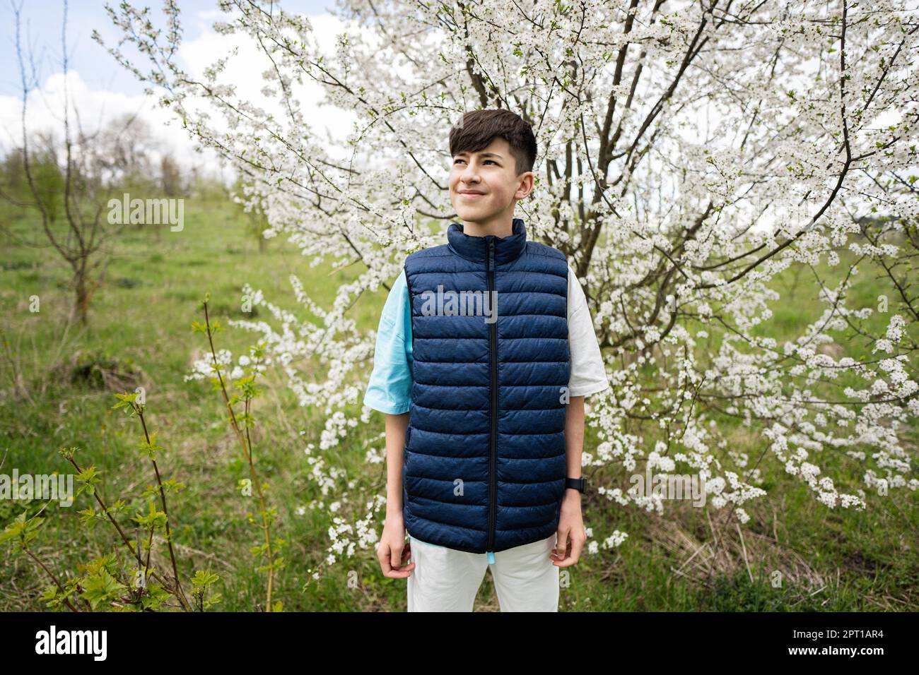 Le jeune garçon porte un gilet sans manches contre un arbre blanc au  printemps Photo Stock - Alamy