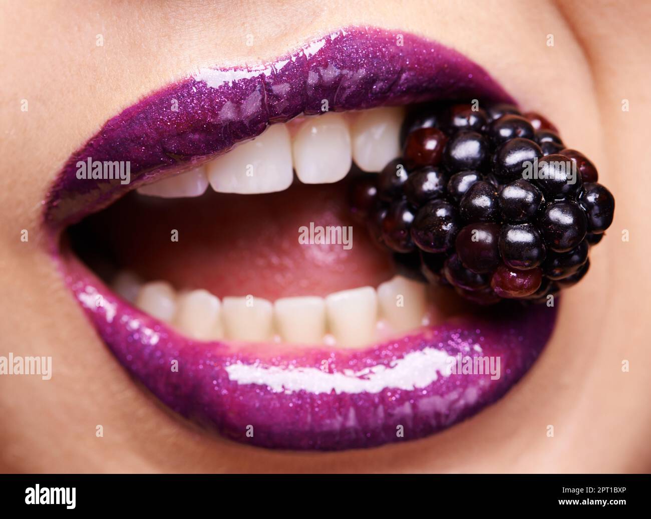 Se laisser tenter par des fruits interdits. une femme portant un rouge à  lèvres violet et piquant dans un blackberry Photo Stock - Alamy
