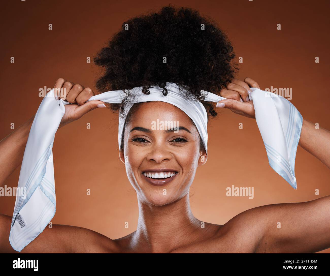 Femme noire, foulard et coiffure avec le portrait de femme esthétique  nouant ses cheveux bouclés sur un fond brun studio. Afro, soins capillaires  et coiffure St Photo Stock - Alamy
