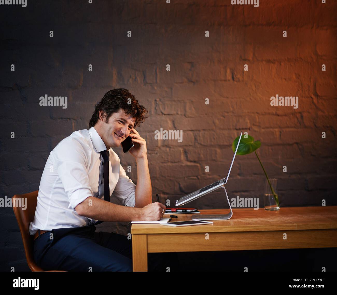 Bien sûr, nous pouvons le faire pour vous. un homme d'affaires parlant au téléphone tout en travaillant tard au bureau Banque D'Images