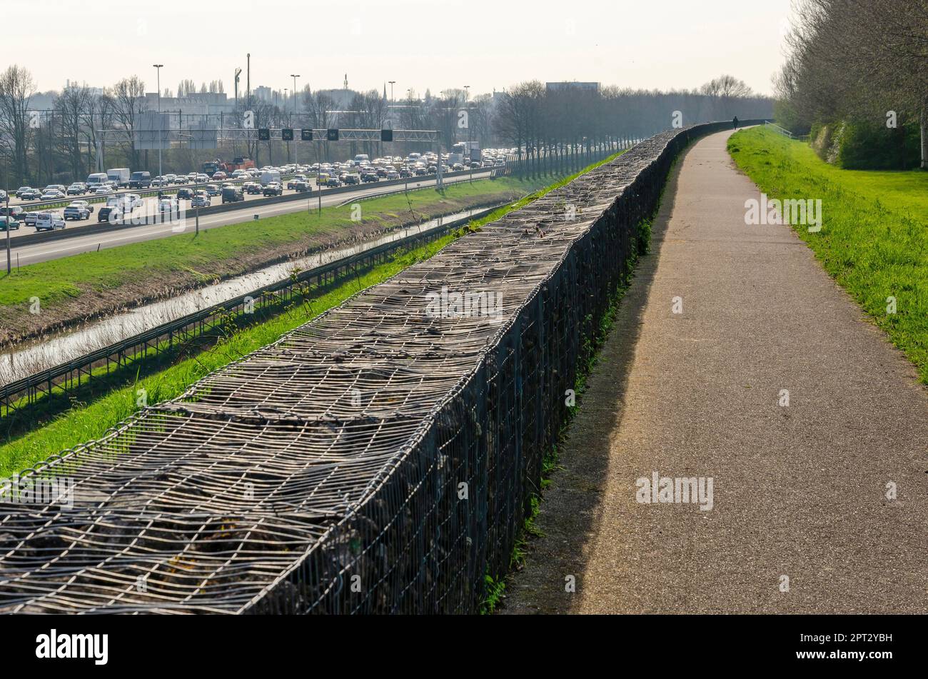 Rotterdam, pays-Bas, 5 avril 2023: Sentier sur la barrière sonore avec vue sur l'autoroute A20, avec un embouteillage dans les deux directions Banque D'Images