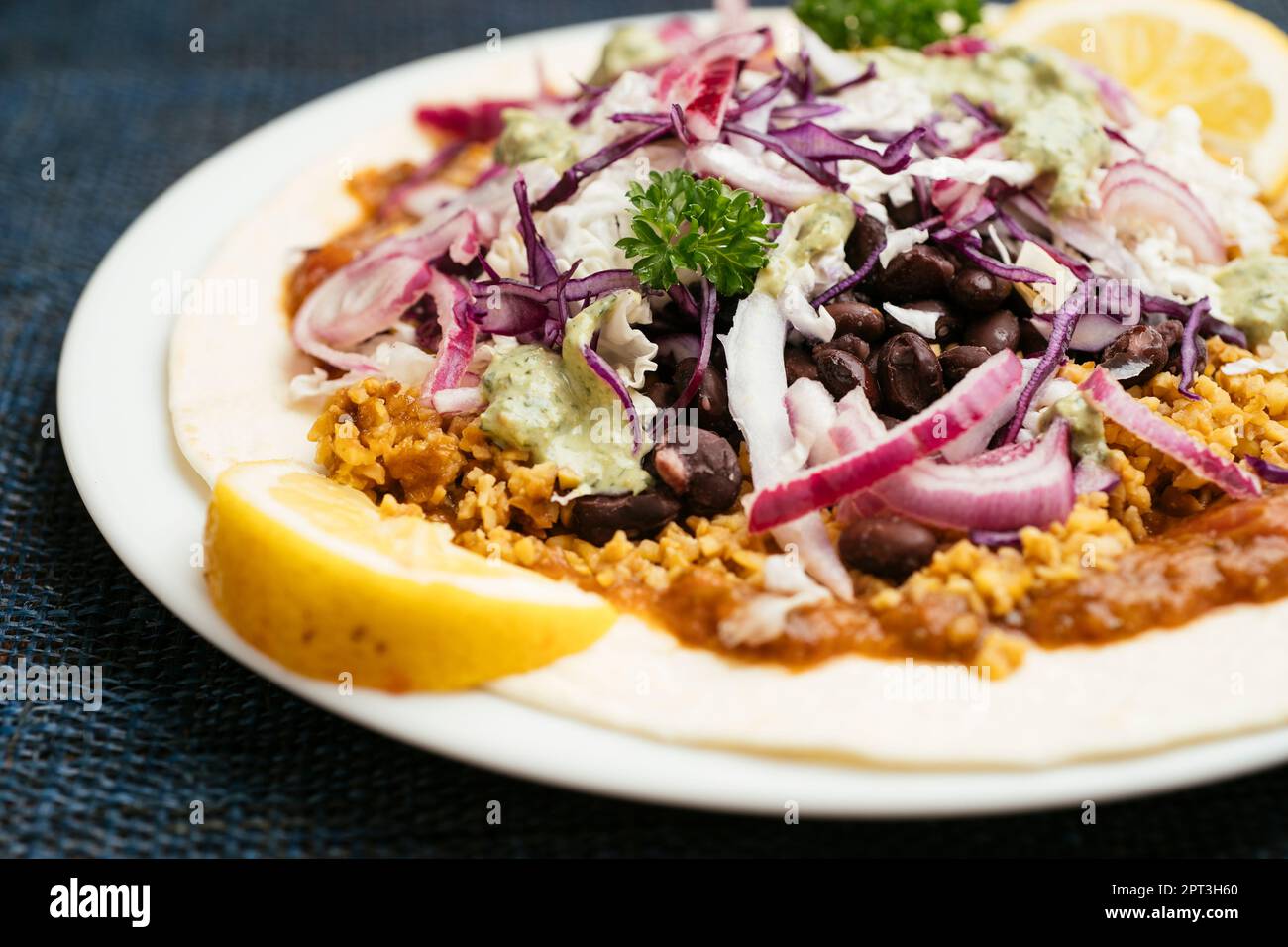 Tostadas avec des granules de TVP, des choux mélangés, des haricots, des oignons et une sauce barbecue au rhubarbe. Banque D'Images
