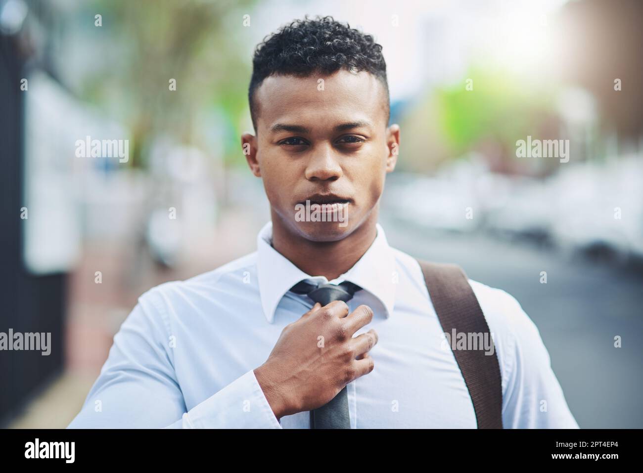 Regardez la pièce pour la respecter. Portrait d'un beau jeune homme d'affaires qui ajuste son cravate pendant qu'il est en ville Banque D'Images